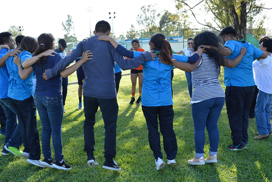 Miembros de la Asociación Mexicana de Fisioterapia se paran en círculo con sus brazos alrededor del otro