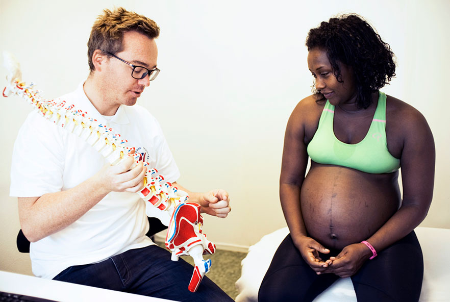 Ein Physiotherapeut behandelt eine schwangere Patientin