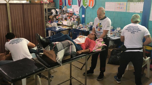Three physical therapists provide support to a patient lying on a bed