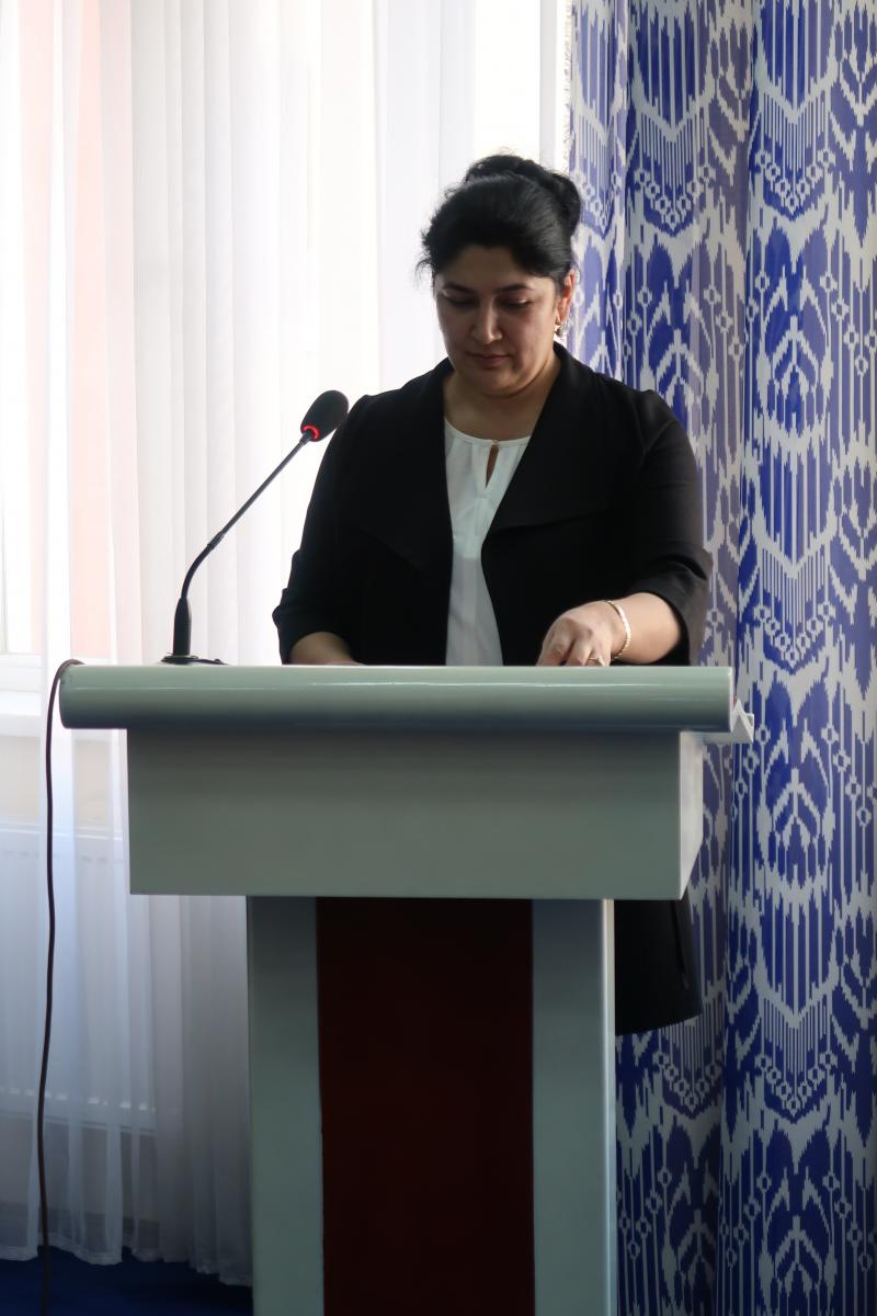 A woman standing a podium, speaking into a microphone