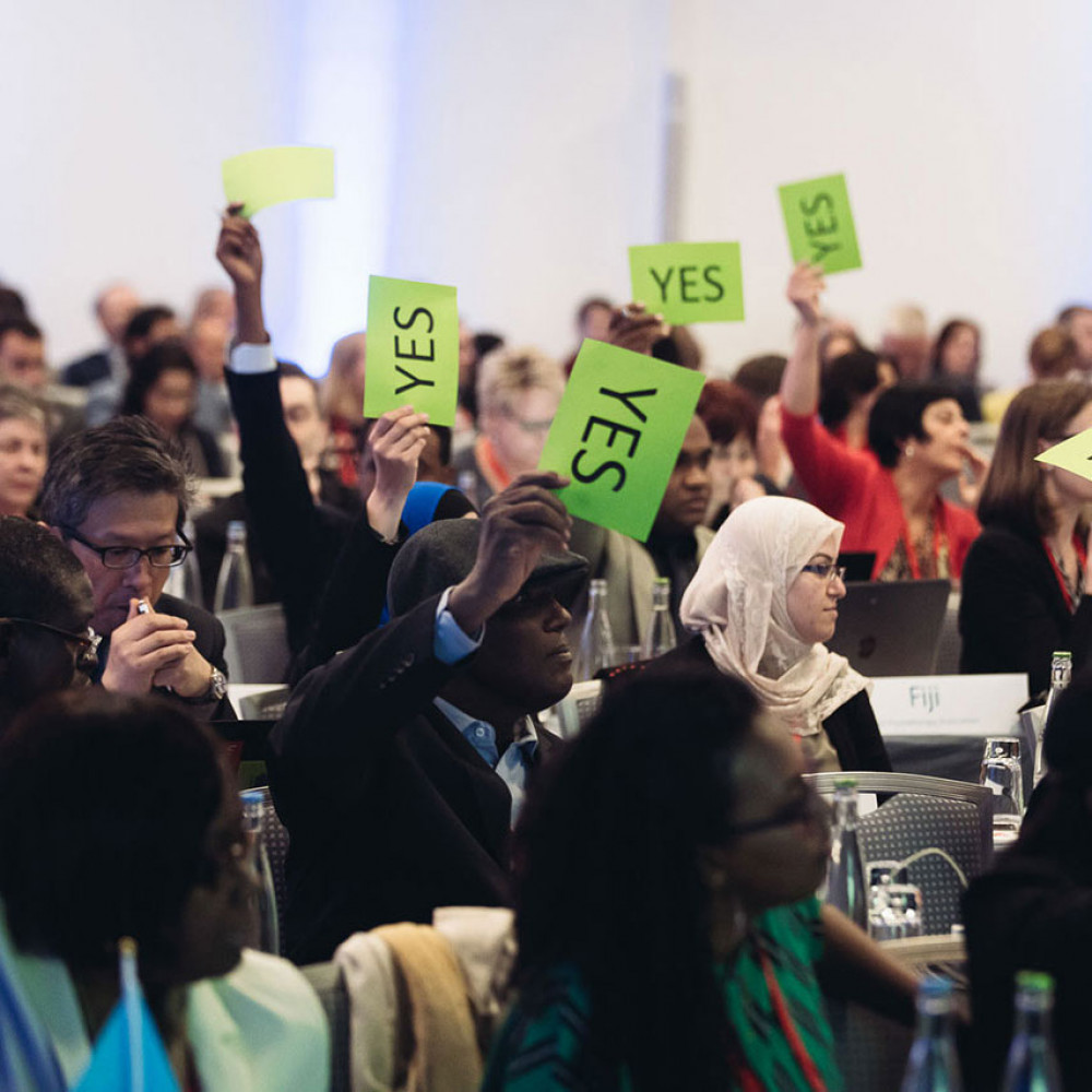 General Meeting attendees hold up 'Yes' signs to vote