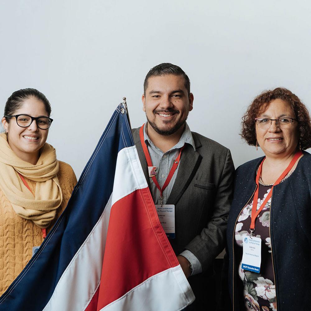 Three people standing together holding the national flag of Costa Rica