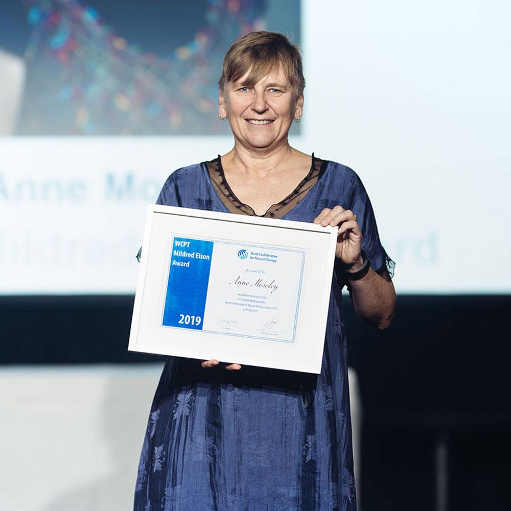 Anne Moseley holding a framed award on stage